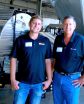 two men in front of an automated farm spraying rig