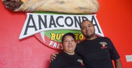 mother and son posing in front of a sign