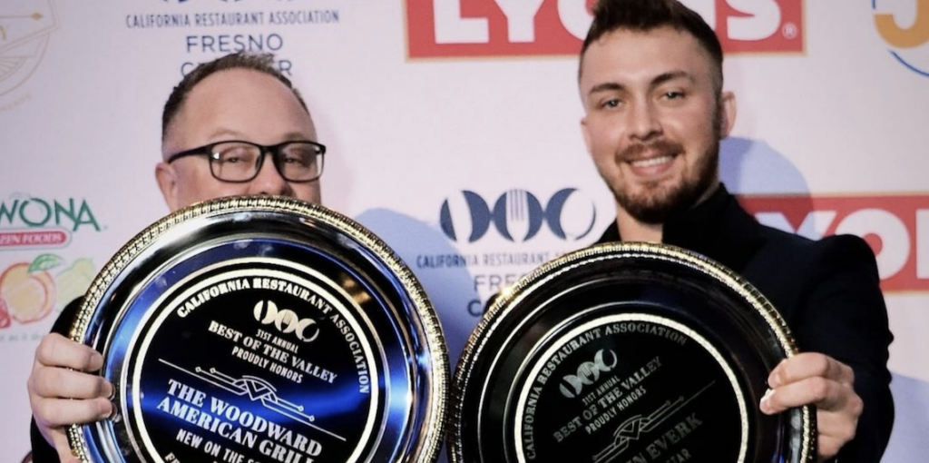 two men holding up awards
