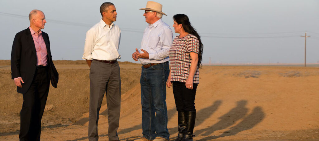 four people standing in a farm field