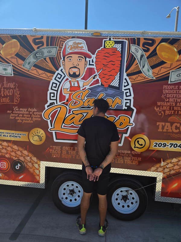 man handcuffed in front of a taco truck