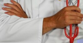 man in lab coat holding a stethoscope