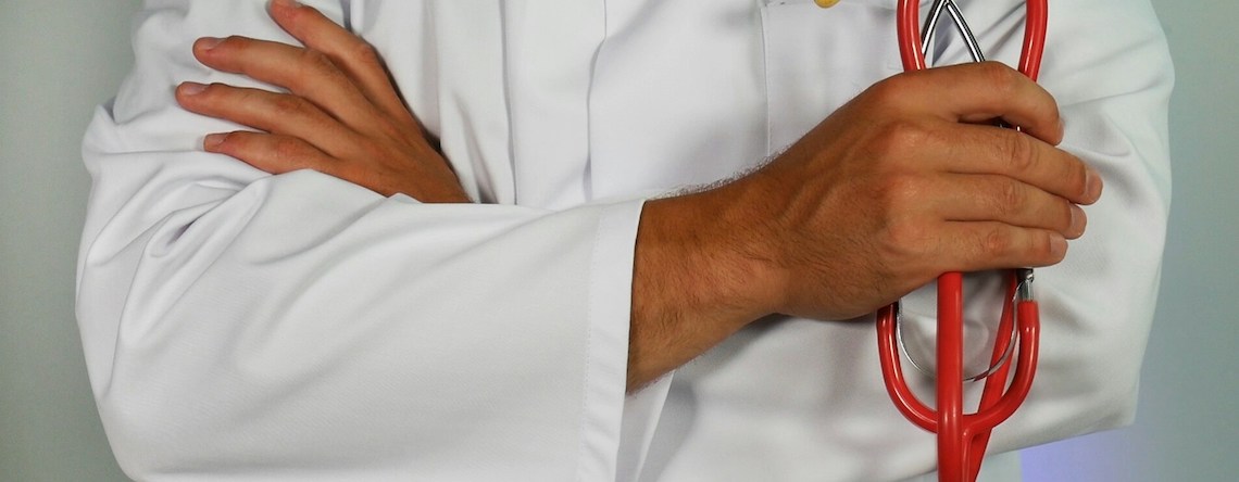 man in lab coat holding a stethoscope