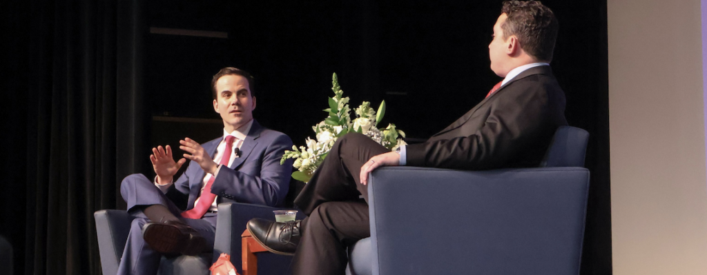 two men chat onstage