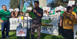man speaking to a group of people holding signs