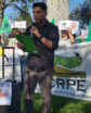 man speaking to a group of people holding signs