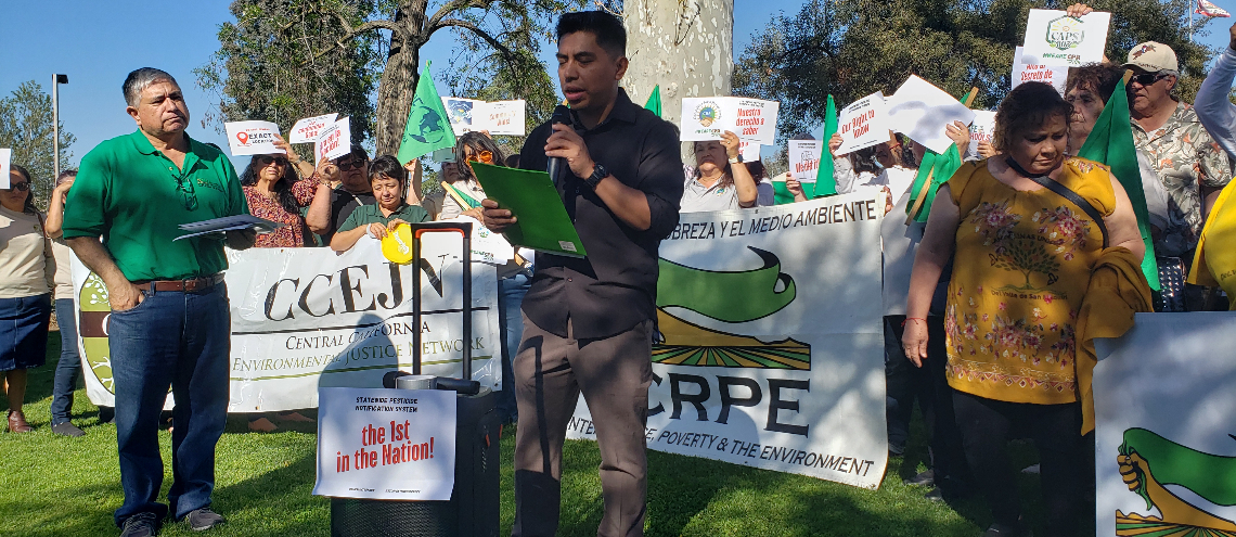 man speaking to a group of people holding signs