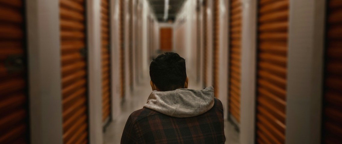 man kneeling in a self storage facility hallway