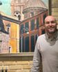 man smiling in front of painting