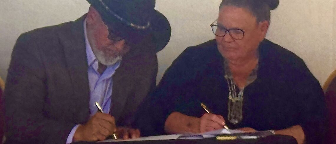 two people signing a document
