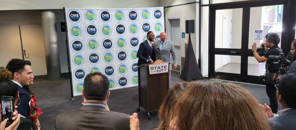 two men behind a podium in front of a crowd