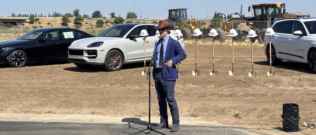 man speaking in a dirt lot
