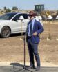 man speaking in a dirt lot