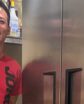 man smiling next to a freezer