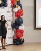 two women pose for a photo in front of a red white and blue backdrop