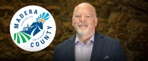 man smiling with a city logo to his right