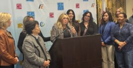 people standing around a woman at a podium