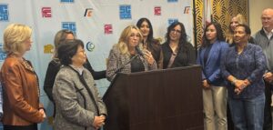 people standing around a woman at a podium