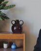 man smiling as he sits next to a book shelf