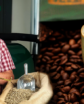 a man grinding coffee beans next to a large cup of coffee
