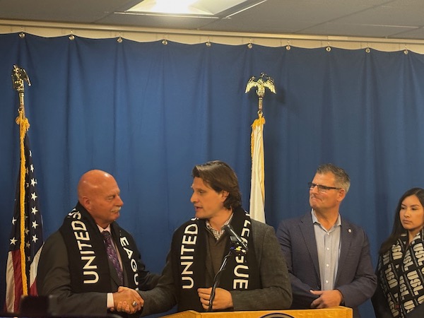 people shaking hands as others look on