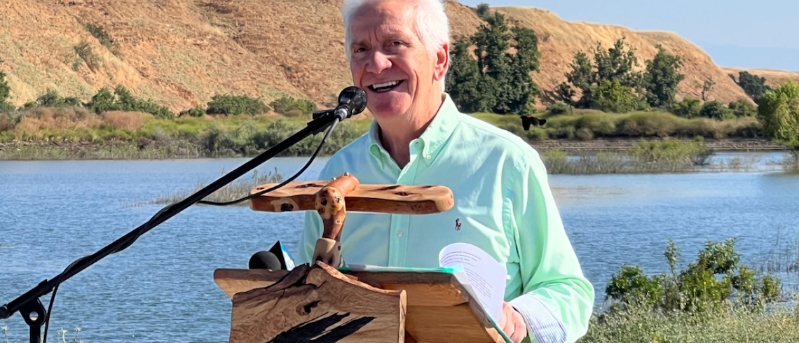 man at a podium in front of a river
