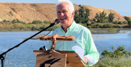 man at a podium in front of a river