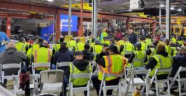warehouse floor with workers in high visibility gear gathered