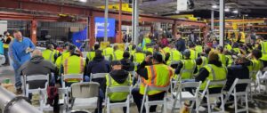 warehouse floor with workers in high visibility gear gathered