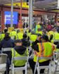 warehouse floor with workers in high visibility gear gathered