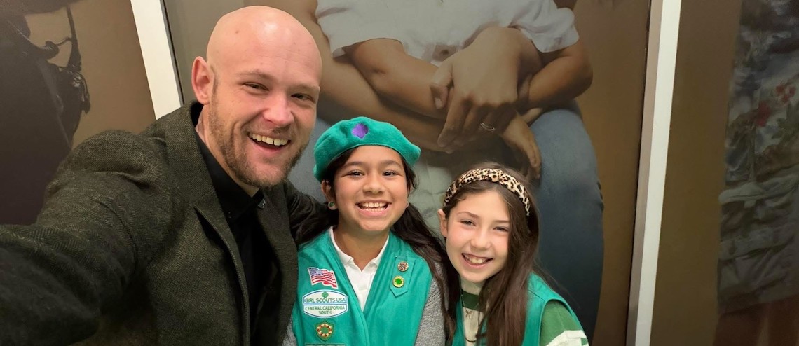 man posing with two girl scouts