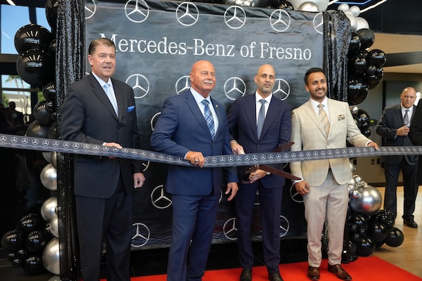 four men in suits about to cut the ribbon of a new dealership