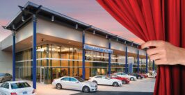 luxury auto dealership behind a red curtain with a hand extended