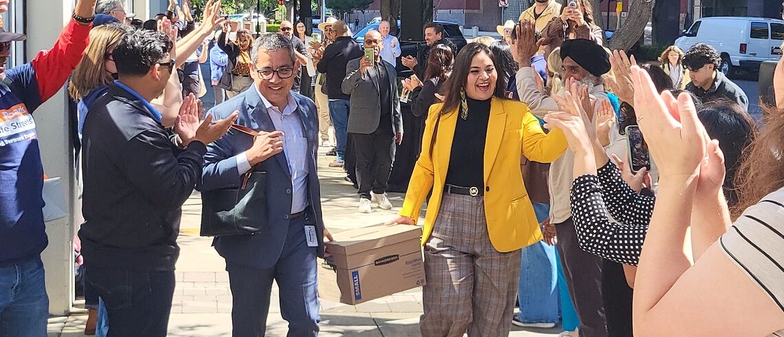 two people carrying a box between two lines of people