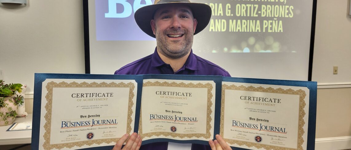 man in cool hat holds three certificates