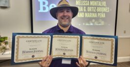 man in cool hat holds three certificates