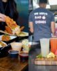 A Jesse Boy branded takeout bag being handed across a counter at the West Hollywood location