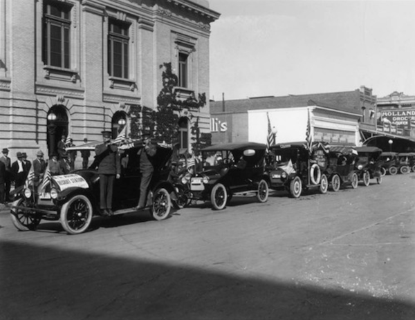 a parade of old cars in black and white