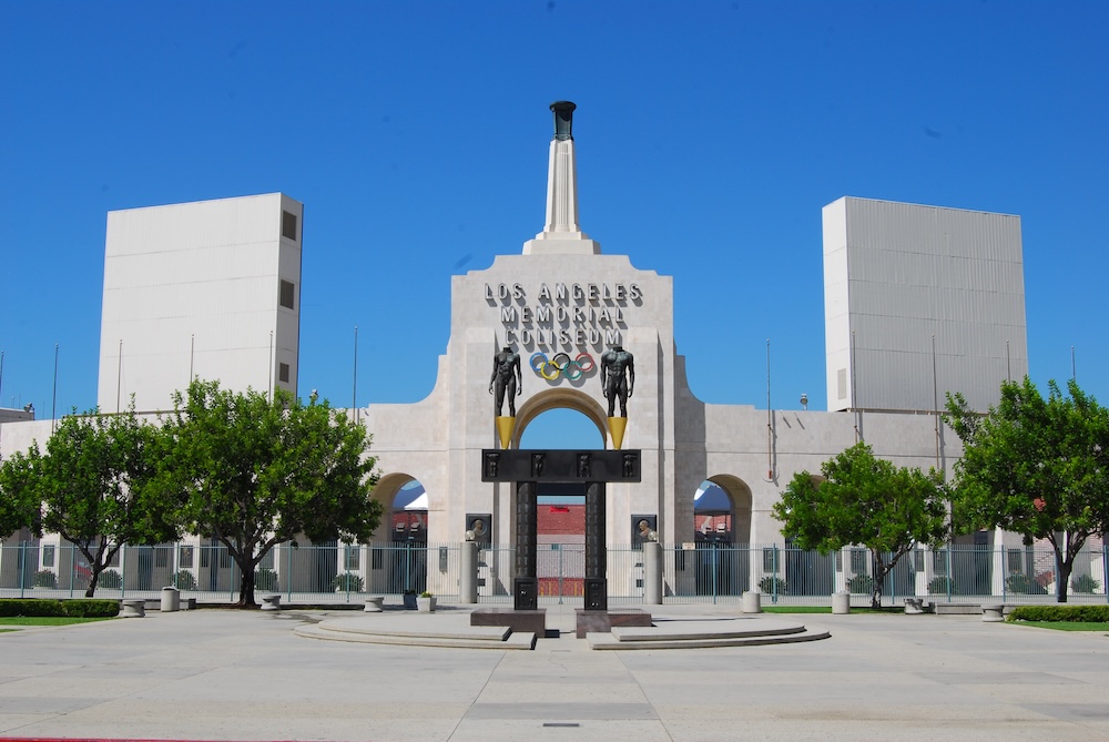 The entrance and facade of the Los Angeles Memorial Coliseum in Los Angeles, with the Olympic rings displayed above the central arch.