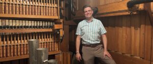 man standing in a pipe organ chamber