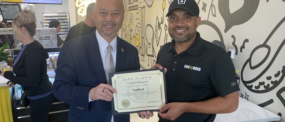 two men posing and holding a certificate
