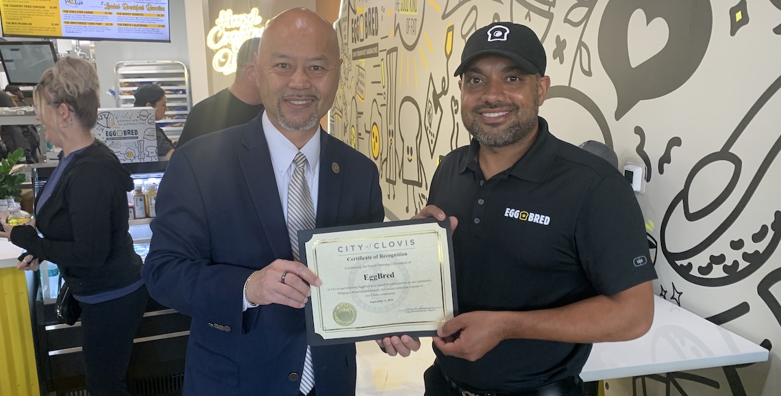 two men posing and holding a certificate