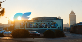 a building with a mural with sunrise and an only fans logo rising over the building