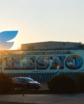 a building with a mural with sunrise and an only fans logo rising over the building