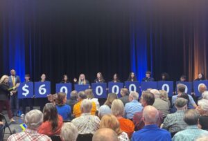 Fresno Pacific University students hold signs displaying $60 million during an announcement of a record gift from an anonymous alumnus.