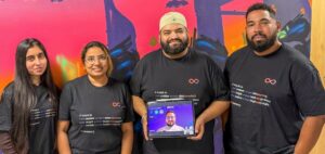 a tech company team consisting of two women and two men, plus a man's face on a tablet