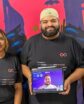 a tech company team consisting of two women and two men, plus a man's face on a tablet