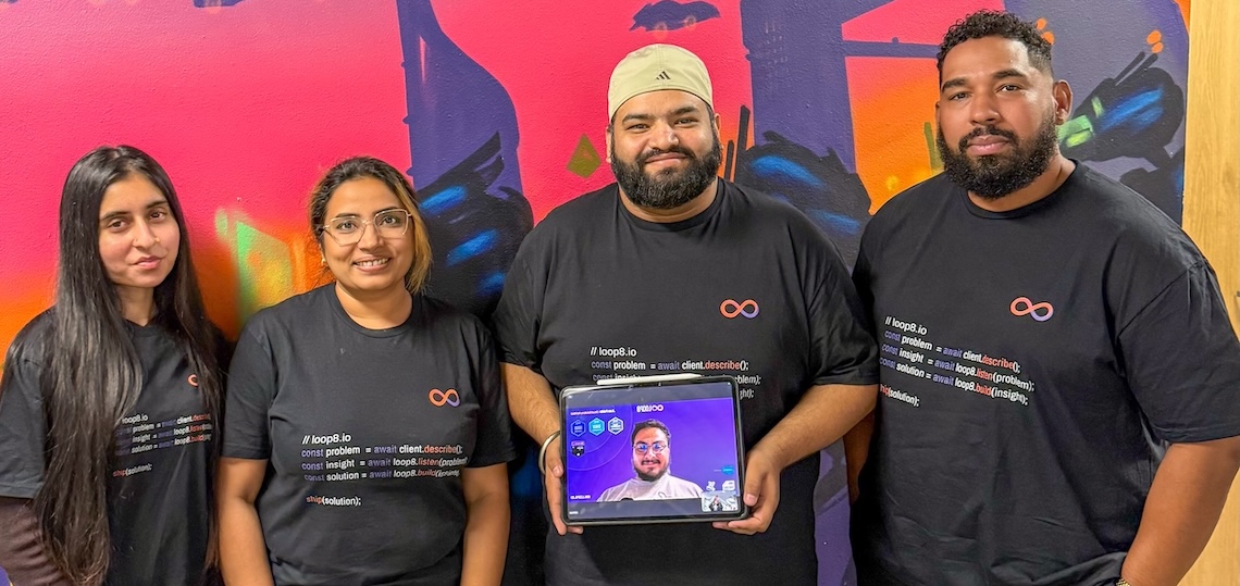 a tech company team consisting of two women and two men, plus a man's face on a tablet
