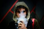 A person exhales vapor while using a vaping device