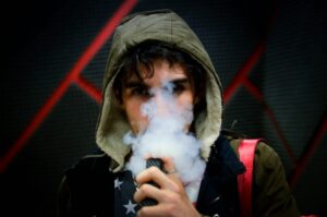 A person exhales vapor while using a vaping device